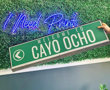 Welcome to Cayo Ocho sign displayed against a leafy wall
