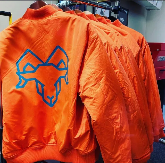 Orange satin jackets with a large blue embroidered animal emblem on the back