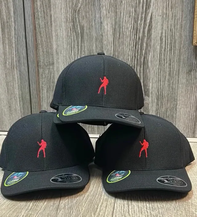 Black caps decorated with a red figure logo displayed against a wood wall
