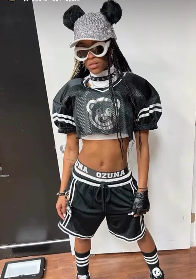 Performer wearing a coordinated black-and-white graphic top and shorts with a sparkling cap