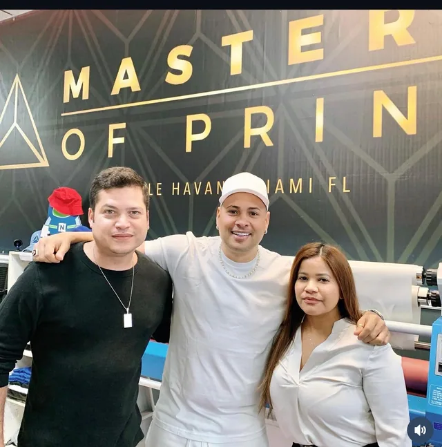 Three people standing in front of the Masters of Print sign inside the shop