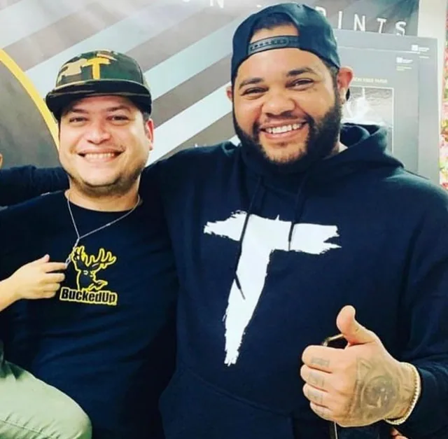 Two people posing together, one wearing a black graphic hoodie