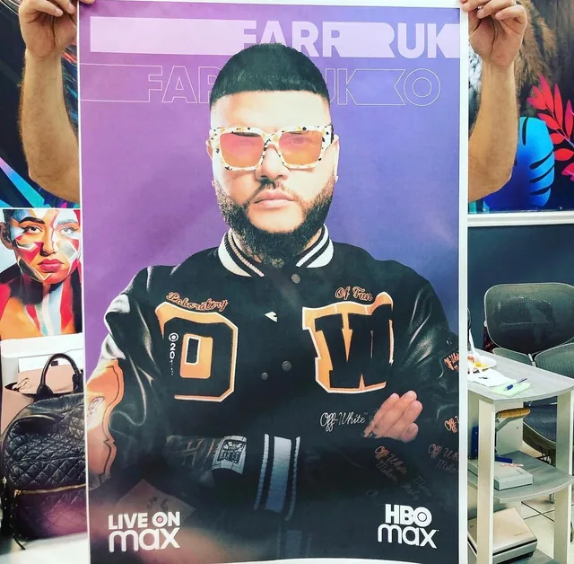 Person holding a colorful printed event poster featuring a performer
