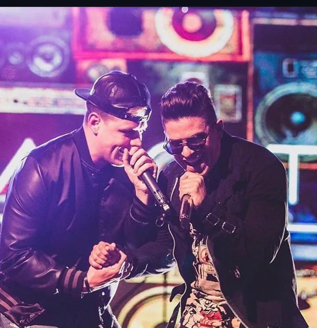 Two performers holding microphones under purple stage lights